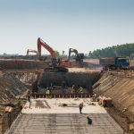 Zware machines en bouwvakkers werken aan een gebouw.