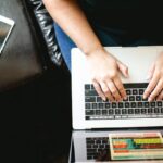 person using MacBook while sitting on chair