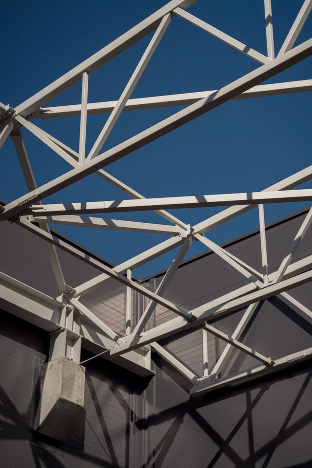 Stalen balken vormen een ingewikkeld raster tegen een heldere blauwe lucht in deze industriële architectuurfoto.